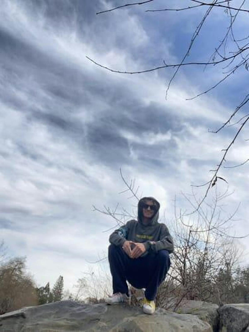 Customer wearing Closing Chapter hoodie outdoors against a moody sky