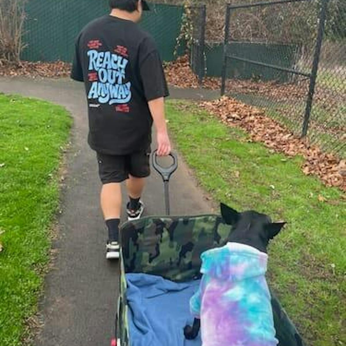 Customer walking a dog wearing the Reach Out Anyway oversized tee, back print visible