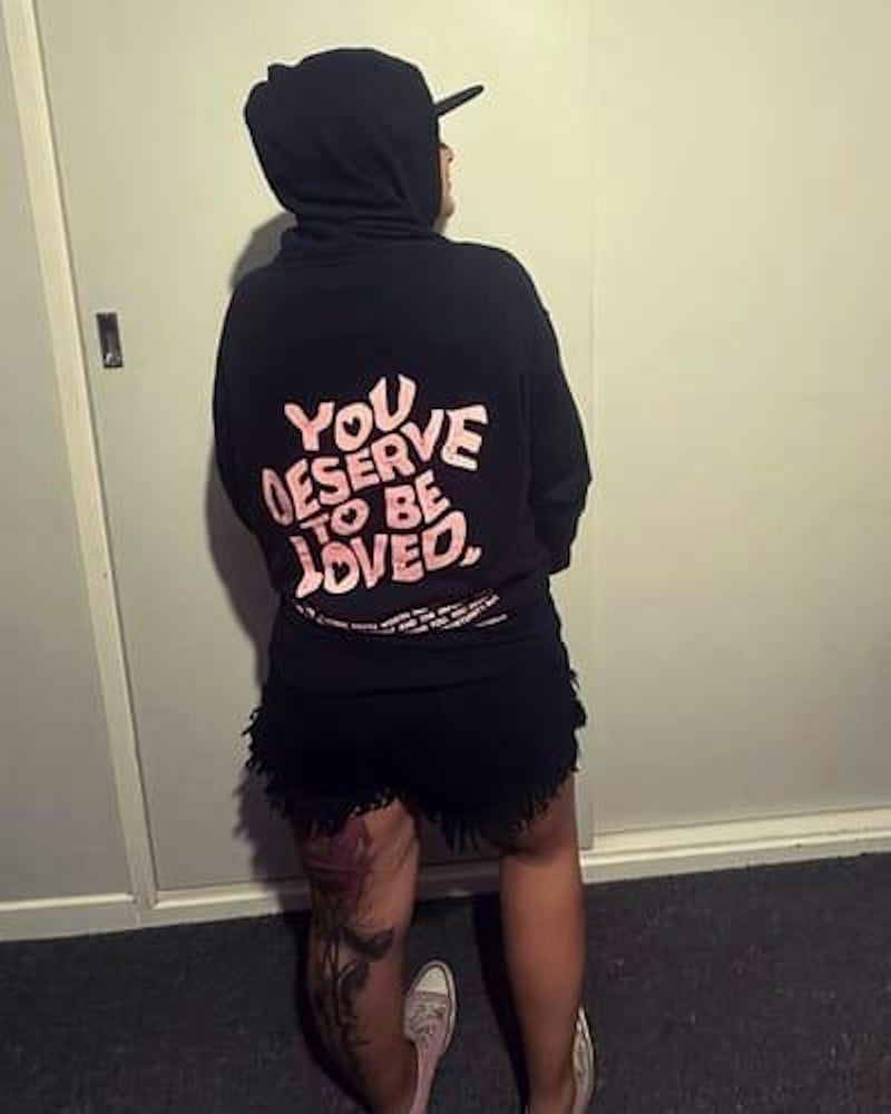 Customer wearing You Deserve To Be Loved black hoodie, back print visible, hood up